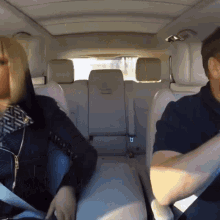 a man and woman sit in the back seat of a car