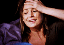 a woman is laying in bed with her hand on her forehead and smiling
