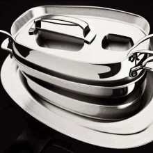 a stainless steel casserole dish with a lid is sitting on top of a stainless steel tray .