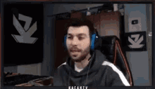 a man is wearing headphones while sitting in front of a computer screen .
