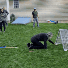 a group of people are playing in a backyard with a goal