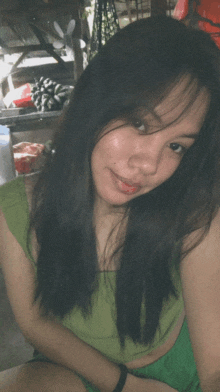 a woman with long black hair is wearing a green shirt