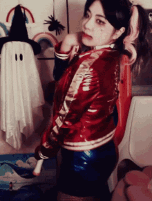 a woman in a harley quinn costume stands in front of a white ghost