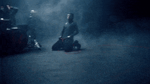 a man is kneeling in front of a drum set with a h on it