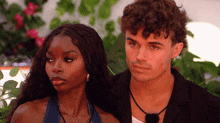 a man and a woman standing next to each other looking at something