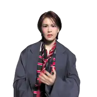 a woman wearing a jacket and tie is making a gesture with her hands