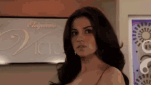 a woman in a bra stands in front of a sign that says elegance