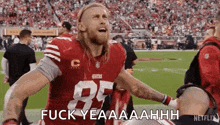 a football player in a red jersey is standing on a field with his arms outstretched .