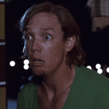 a man wearing a green shirt is making a funny face