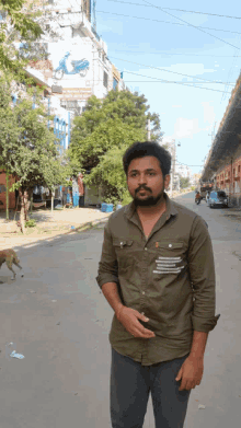 a man in a green shirt stands on a street with a dog