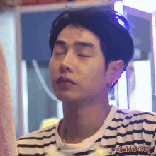 a man with his eyes closed is wearing a striped shirt with judlek702 written on it