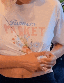 a woman wearing a white farmers market shirt