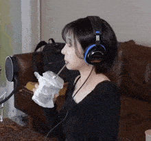 a woman wearing headphones is drinking from a plastic cup through a straw
