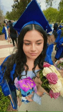 a woman in a graduation cap and gown holds a bouquet of flowers and a purple cap that says class of 2024