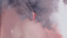 a woman in a pink dress is surrounded by pink smoke