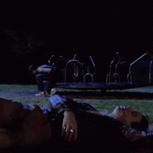 a man is standing next to a woman who is laying on the ground