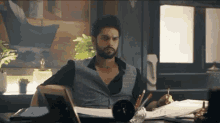 a man with a beard is sitting at a desk with a picture frame on it