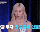 a woman with long blonde hair has a name tag that says ' 한동 ' on it