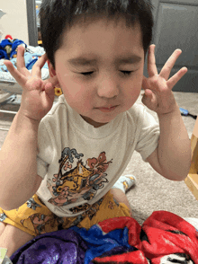 a young boy wearing a white shirt with a tiger on it making a peace sign