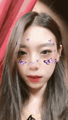 a woman with butterflies on her face looks at the camera