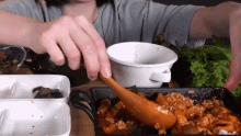 a person is eating food with a wooden spoon and a bowl .