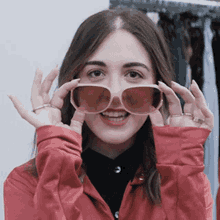 a woman wearing sunglasses and a red jacket is making a funny face