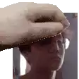 a close up of a person 's head with a hand on it . the person is wearing glasses and a hat .