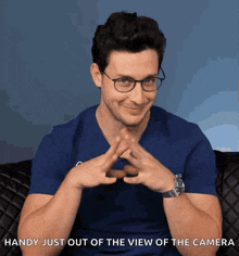 a man wearing glasses and a watch says " handy just out of the view of the camera " in front of his face