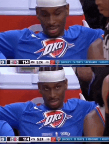 a basketball player wearing a okc jersey sits in the stands during a game