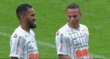 two soccer players on a field with one wearing a shirt that says ' coca cola ' on it