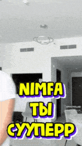 a person standing in a room with a sign that says nimfa tbi cymepp