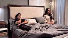 a man and a woman are laying on a bed and laughing