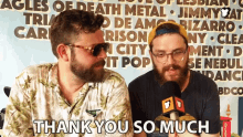 two men are sitting in front of a sign that says ' thank you so much '