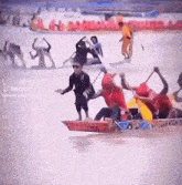 a group of people are rowing boats in the water and one of them is wearing a red shirt .
