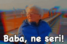 a man in a blue jacket stands on a bridge with the words baba ne seri written below him