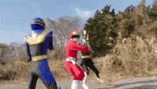 a group of power rangers are standing on a dirt road .