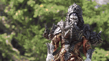 a statue of a monster is standing in front of a green forest