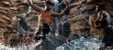 a group of men are standing in front of a waterfall in a cave .