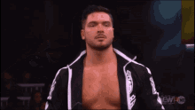 a wrestler is smiling and pointing at his ear while wearing a black and white jacket that says tnt