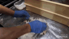 a person wearing blue gloves is kneading a dough on a counter made in animotica