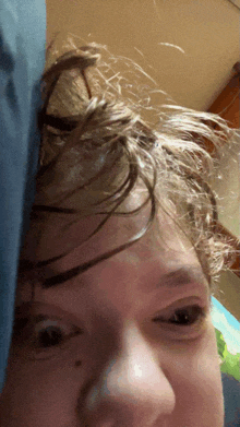 a close up of a person 's face with a blue pillow in the background