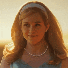 a woman wearing a headband and a pearl necklace