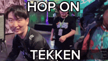 a man in a tekken shirt is dancing in front of a screen that says hop on tekken