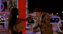 a man in a gold suit is dancing with a woman in a gold dress