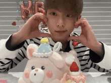 a person making a heart with their hands in front of a cake that has the letter h on it