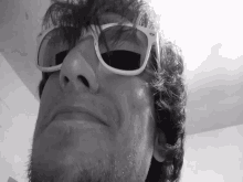 a man wearing white sunglasses makes a funny face in a black and white photo