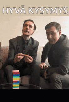 two men in suits are sitting on a couch with a stack of lego blocks in front of them and the words hyva kysmys