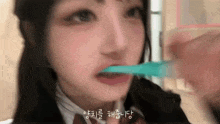 a girl is brushing her teeth with a blue toothbrush