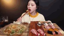 a woman is eating noodles and sushi at a table with chopsticks