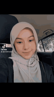 a woman wearing a hijab is sitting in a car with a tiktok watermark